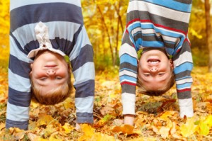Two kids Standing on their hands in a pile of leaves